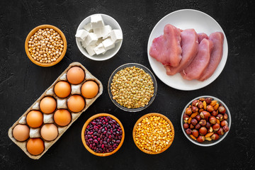 Food for sportsmen. Legumes, nuts, low-fat cheese, meet, eggs on black background top view