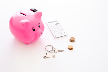 Money for buy car. Moneybox in shape of pig near keychain in shape of car, coins, calculator on white background copy space