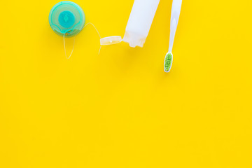 Set for daily teeth care. Toothbrush, tooth paste, dental floss on yellow background top view copy space