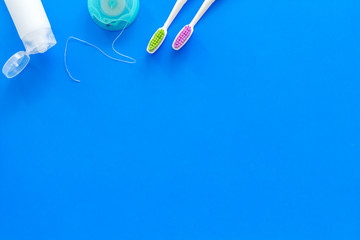 Set for daily teeth care. Toothbrush, tooth paste, dental floss on blue background top view copy...