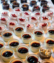 Closeup many dessert jar rowed up on buffet table with fresh fruits jelly and cream