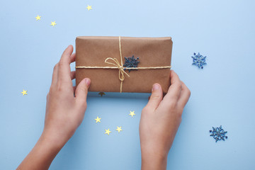 Gift box in the hands of a child on blue background with copy space