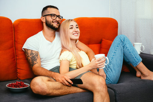 Happy young couple watching TV series together at home