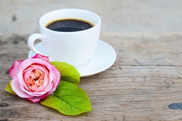 close up shot,black coffee in white coffee cup and beautiful pink rose on blue and  old rustic wood background, morning breakfast concept, top view with copy space for text