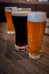Three cold Glass of kraft Beer standing on wooden table at a bar. Foam on the Stout beer.