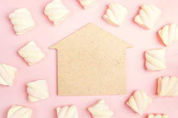 House symbol with spiral marshmallows on pink background. Copy space, flat lay, top view.