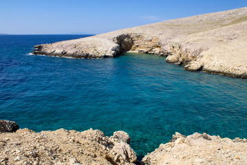 Cliff in sea with small beach and blue sky, island Krk, Croatia