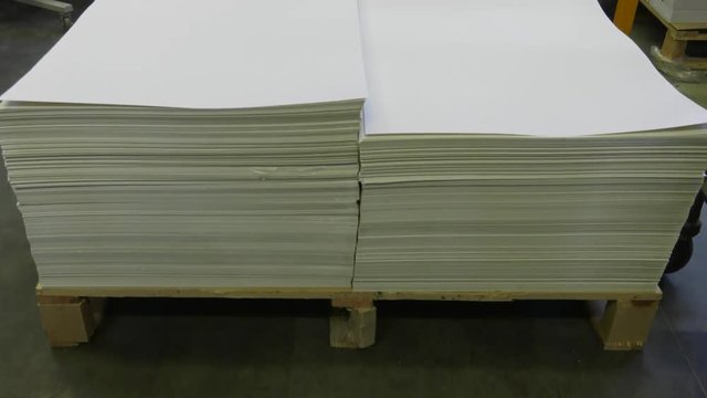 Big sheets of paper lie on a pallet. Panning the camera.