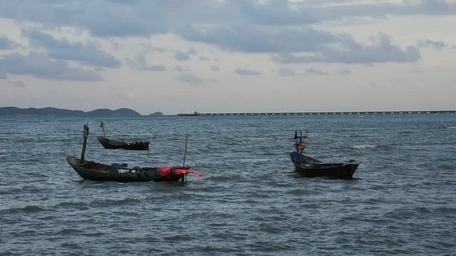 Wooden fishery boat floating and stop wait for go to catching fish in the sea in evening time at Ban Pae beach in Rayong, Thailand