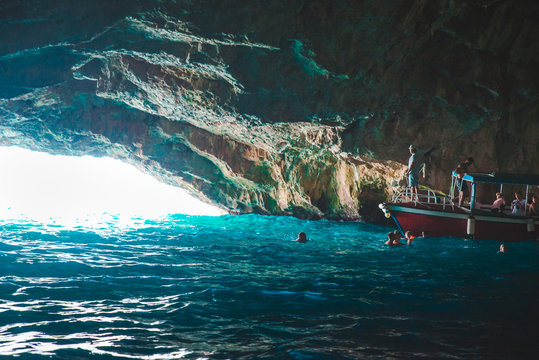 boat with group of tourists in beautiful grotto with azure transparent water