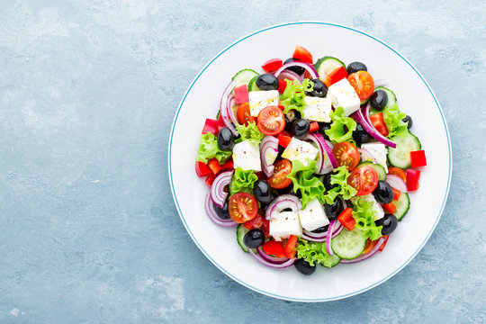 Greek salad of fresh cucumber, tomato, sweet pepper, lettuce, red onion, feta cheese and olives with olive oil