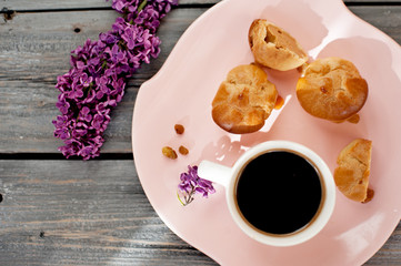 Cup of coffee, cakes and branch of a lilac on a gray wooden background