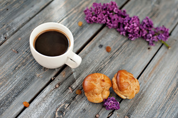 Cup of coffee, cakes and branch of a lilac on a gray wooden background