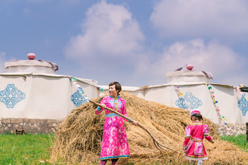 Mongolian mother and daughter working in front of the grass