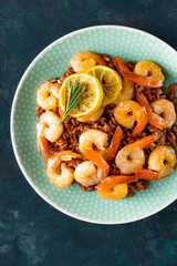 Prawns roasted on grill and boiled brown rice on plate. Grilled shrimps, prawns with rice. Seafood. Asian cuisine. Top view. Dark background