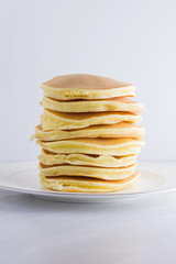 Pancakes on a white background. Many pancakes on a white plate with copy space. Delicious dish for breakfast. Festive food