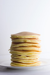 Pancakes on a white background. Many pancakes on a white plate with copy space. Delicious dish for breakfast. Festive food