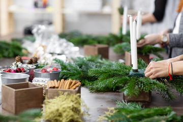 A woman decorates a Christmas arrangement with candles. Hands close-up. Master class on making decorative ornaments. Christmas decor with their own hands. The new year celebration. Flower shop