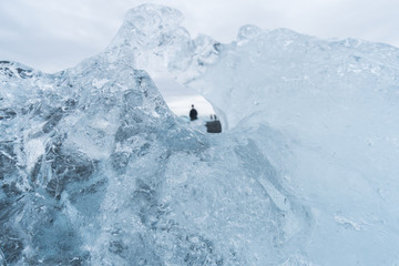 Looking through the hole in an iceberg gives a unique view of tourists on Diamond Beach in Iceland.