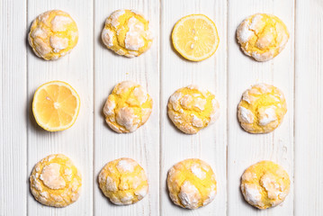 Homemade lemon crinkle cookies with powdered sugar icing. Cracked citrus biscuits on white wooden  background - obrazy, fototapety, plakaty