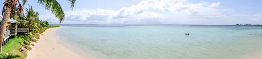 Panorama over Manase Beach, Savai'i Island, Samoa, South Pacific - with people in water and traditional beach fale accommodation © corners74