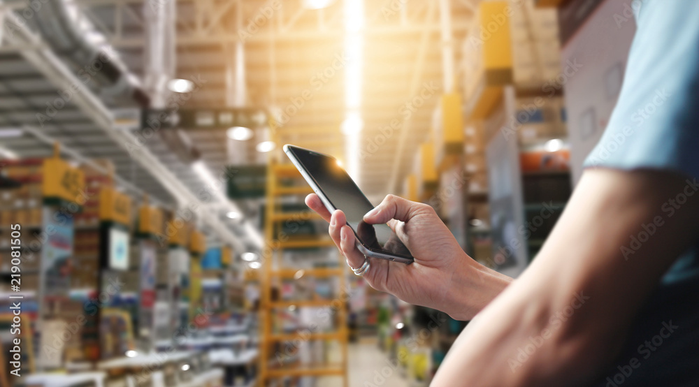 Poster Factory worker using application on mobile smartphone to operate automation for modern trade. Checking order in large warehouse. Import and export the shipping cargo.