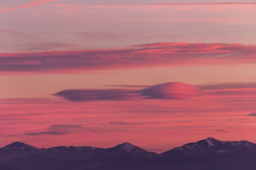 A view of some mountains top, beneath a beautiful, warm colored sky at sunset