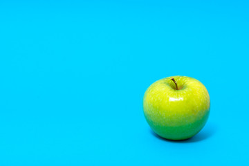 Green fresh apple isolated on blue background.