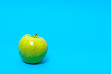 Green fresh apple on blue background