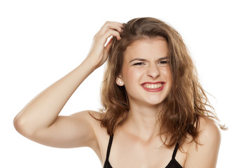 Young woman scratching her head on white background