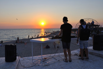 Obraz premium DJ plays music on the beach at sunset