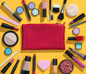 Beauty background with makeup cosmetic products. Photo of red makeup bag with cosmetic products on yellow background. Copy space for your text