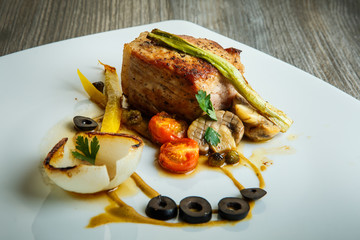 roasted meat decorated with grilled vegetables and black olive