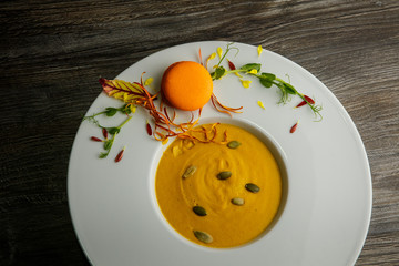 top view of fresh pumpkin cream soup with orange macaroon decoration
