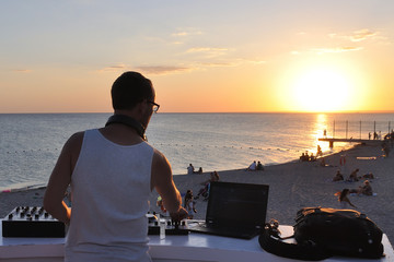 DJ plays music on the beach at sunset