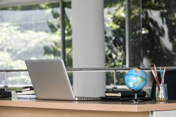 Business office table with laptop earth model on wooden table. Selective focus.