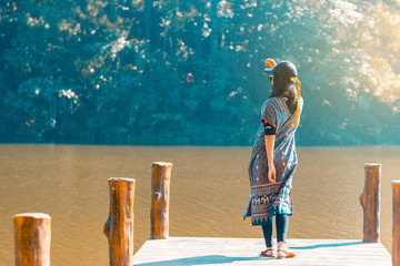 Asian woman standing alone on wooden bridge in front lake ,Thailand