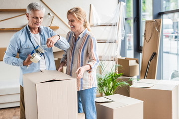 happy senior couple packing cardboard boxes during relocation
