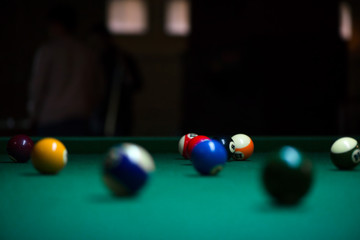 Sport billiard balls on green billiard table in pub. On going billiard game. Competitive players trying to find out the winner of the round