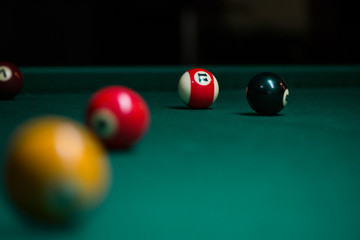 Sport billiard balls on green billiard table in pub. On going billiard game. Competitive players trying to find out the winner of the round