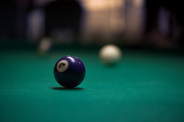 Sport billiard balls on green billiard table in pub. On going billiard game. Competitive players trying to find out the winner of the round