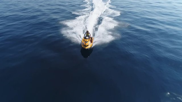 Aerial shot of young man riding on a jet ski. Jet ski cruising at sea