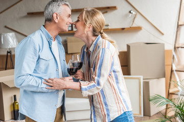 side view of happy senior couple drinking wine during relocation in new house