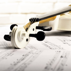 Close view of a violin and musical notes near white brick wall