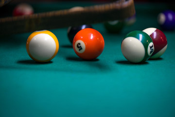 Sport billiard balls on green billiard table in pub. On going billiard game. Competitive players trying to find out the winner of the round