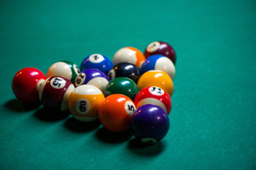 Sport billiard balls set arranged in shape of triangle on green billiard table in pub. Players are ready for the first hit of the round to start the billiard game