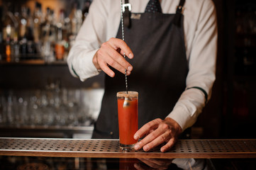 Bartender stirring a bloody mary in the classical cocktail glass