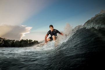 Young active man riding on the wakeboard on the bending knees - obrazy, fototapety, plakaty