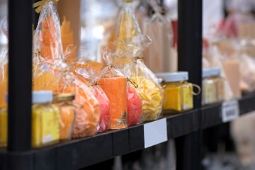 Natural, handmade candles in different shapes standing in shelf sorted by colors. Concept of gifts  