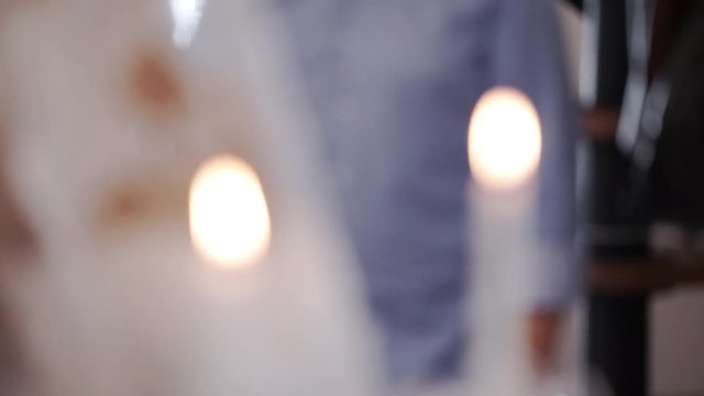 Bride and groom holding candles in church at christianity wedding ceremony blur